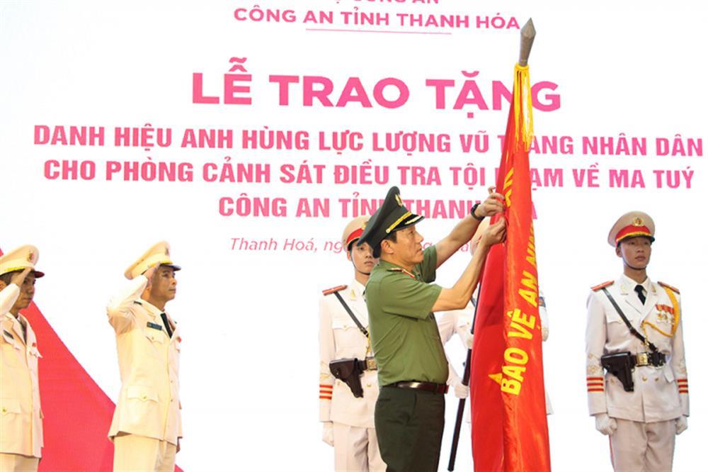 Minister Luong Tam Quang attaches insignia of the “Hero of the People’s Armed Forces” title to the division’s traditional flag.