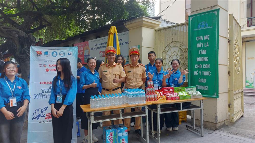 Police officers offer bottled drinking water and hand fans to candidates.