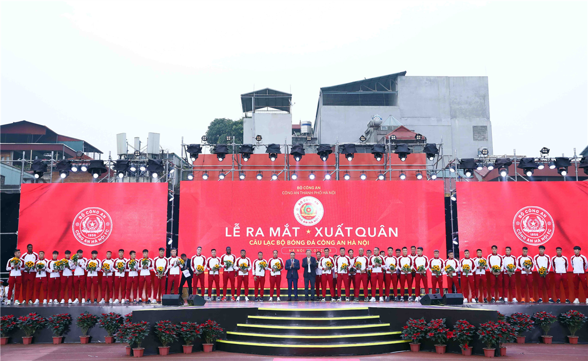 Minister To Lam and Chairman of Hanoi People's Committee Tran Sy Thanh present flowers to the coaching board and players of the Hanoi Police Football Club.